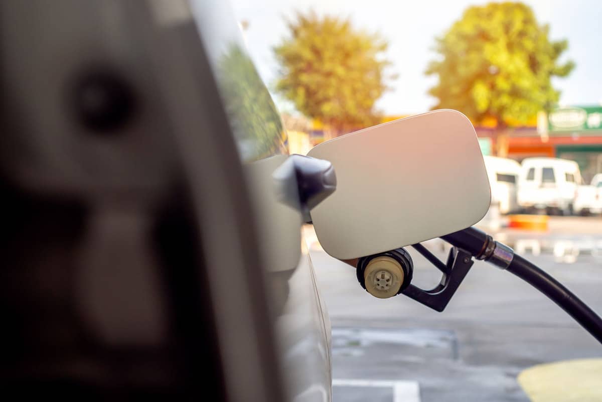 Car refueling on petrol station. Pumping gasoline fuel behind white fuel cap holder.