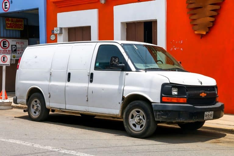 A Chevy Express van parked outside a building, How Long Is A Chevrolet Express Van? [And How Much Does It Weigh?]