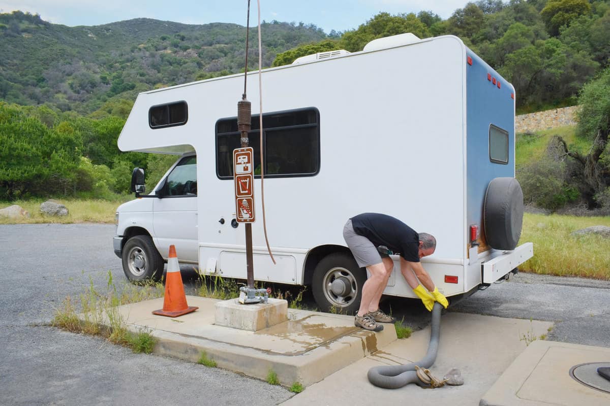 A man dumping waste water in his small motorhome to a designated dumping station