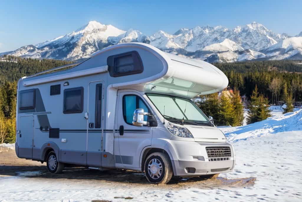 An RV parked on the camping ground of a snowy mountain