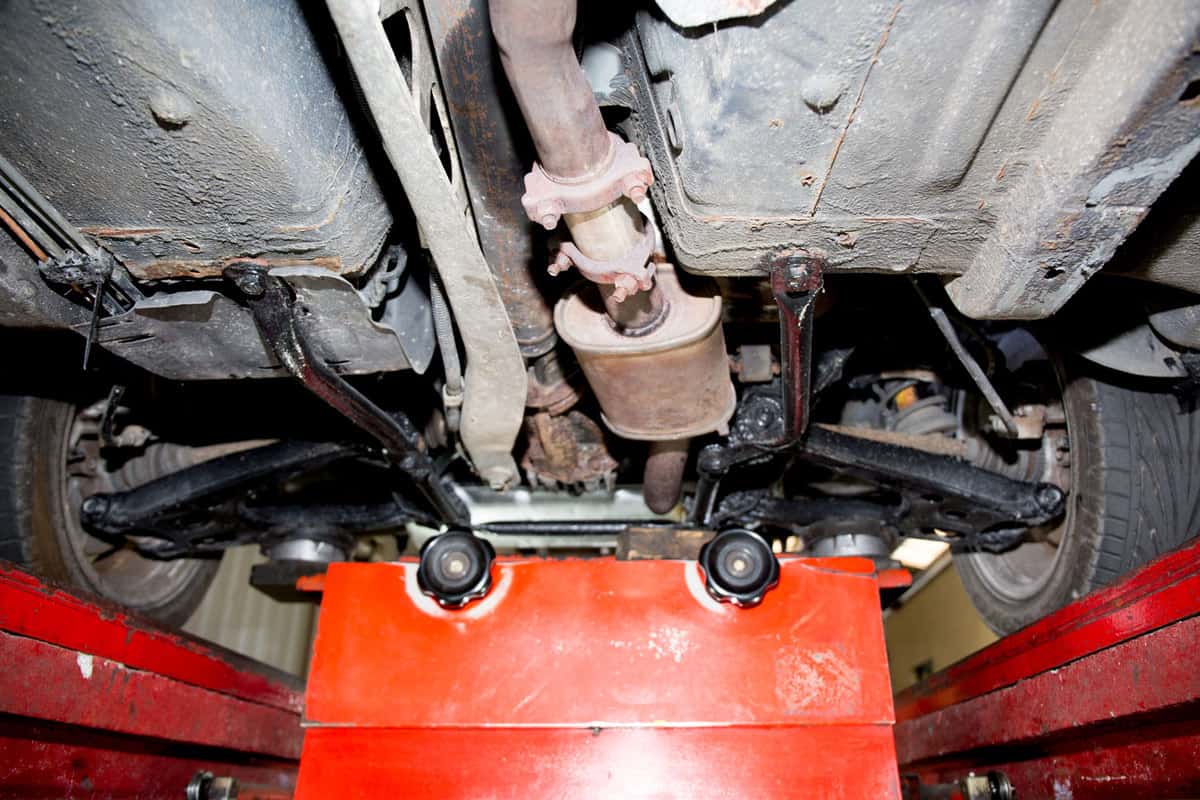 An underside photo of a car showing the catalytic converter on the middle and the back suspension on the back, How Big Is A Catalytic Converter?