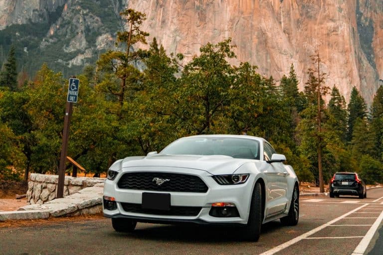 Beautiful white Ford Mustang GT parked in the heart of the Yosemite National park with amazing half dome cliffs around it, Does A Ford Mustang Have Adaptive Cruise Control?