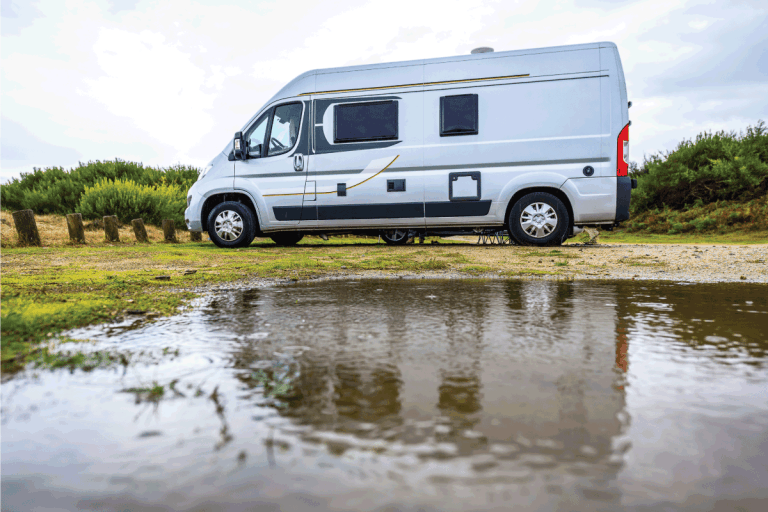 Campervan or motorhome camping on rainy day with rain puddles. How Much Does It Cost To Replace RV Water Heater