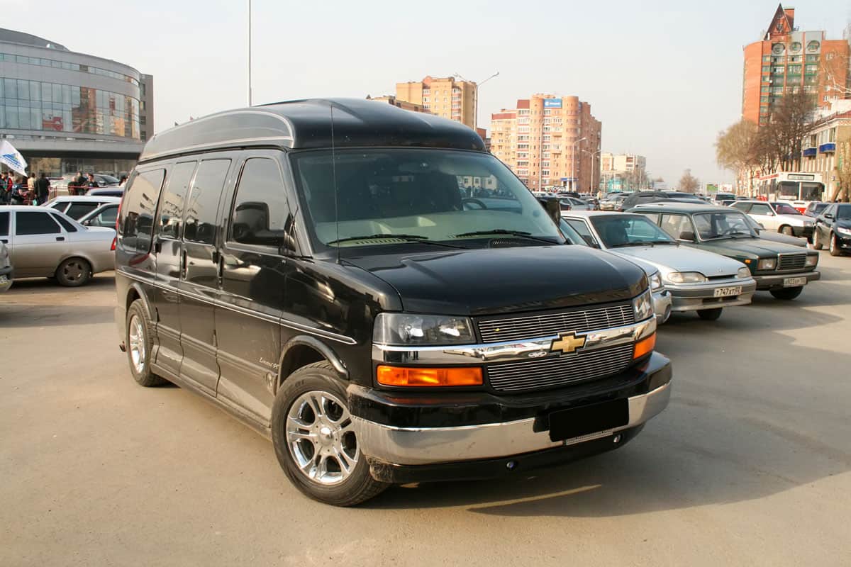 Chevy Express Van black glossy paint in the middle of the town sunny afternoon