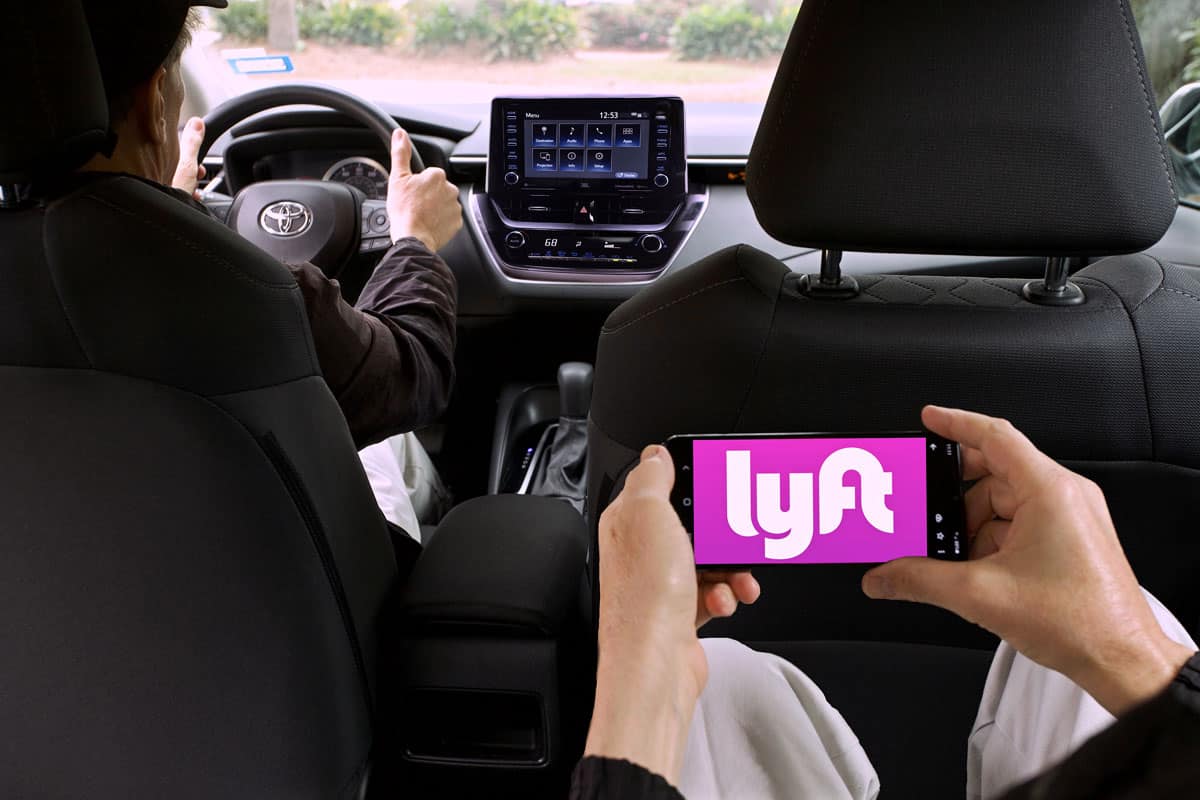 car passenger holding smartphone showing Lyft app on phone