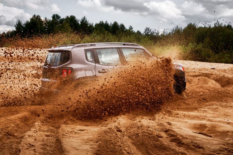 A Jeep Renegade trekking on a muddy and sandy track, How To Turn Off The Parking Brake On A Jeep Renegade