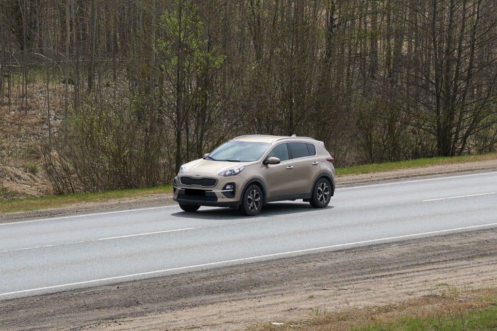 A beige colored Kia Sportage moving along the highway