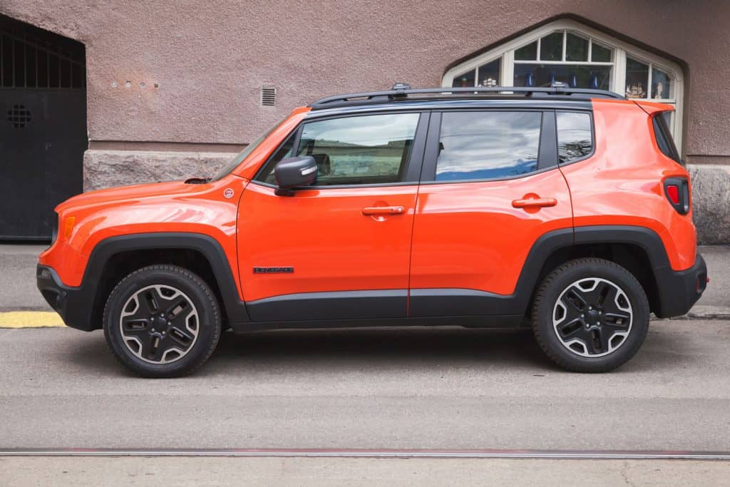 Light red colored jeep renegade on the side of a building