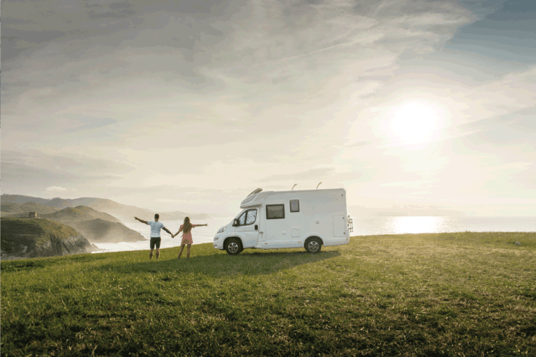 Young couple traveling with their motor home standing by the sea with arms raised. How Big Is My RV's Grey Water Tank
