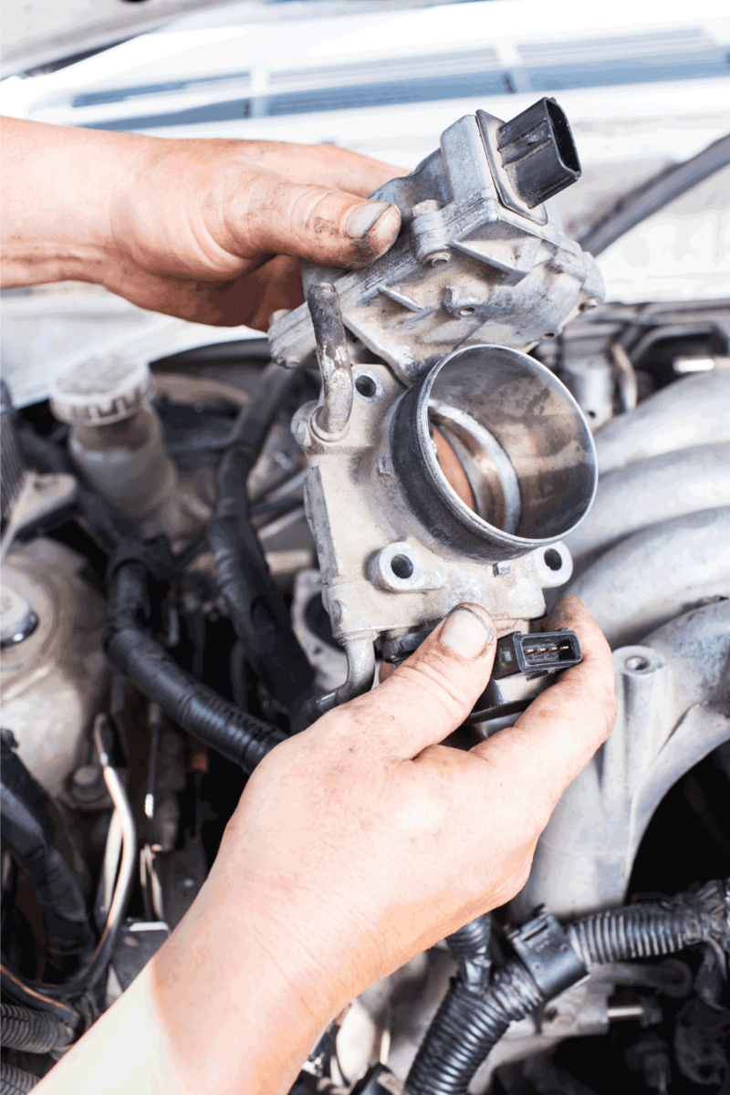 car throttle body being held in hand by a car mechanic