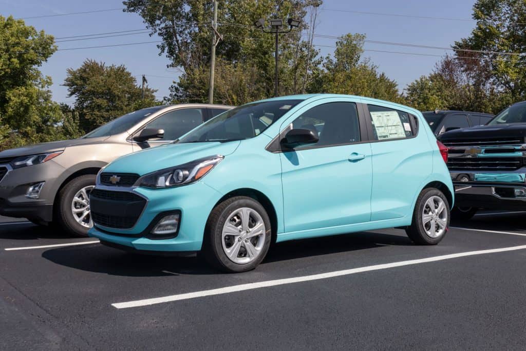 A light blue colored Chevy Spark on the parking lot