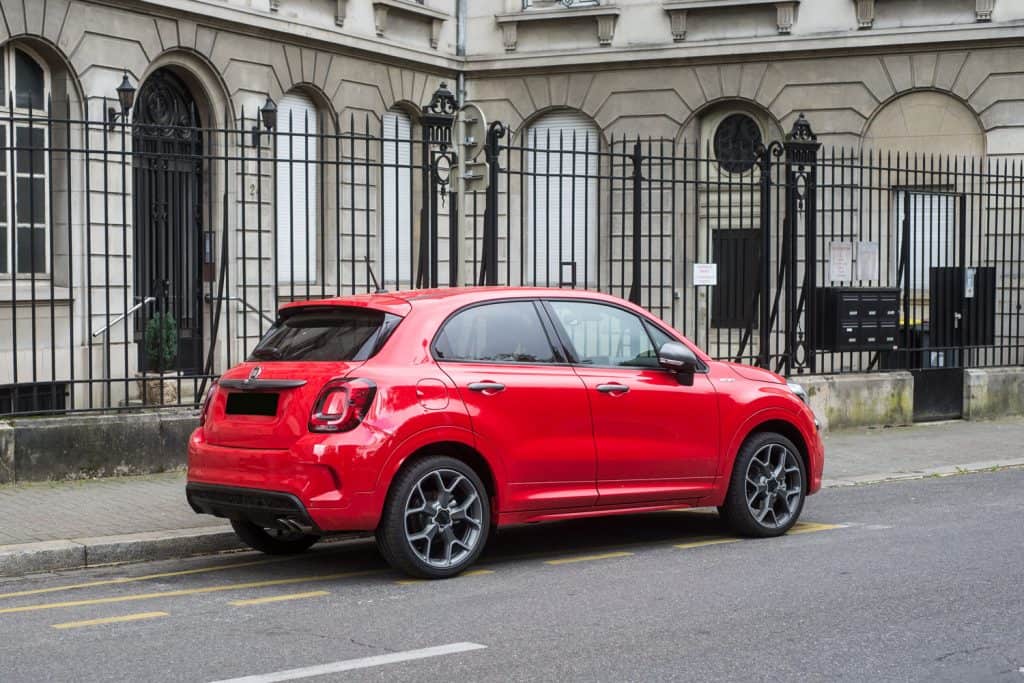 A red Fiat 500X parked next to a palace
