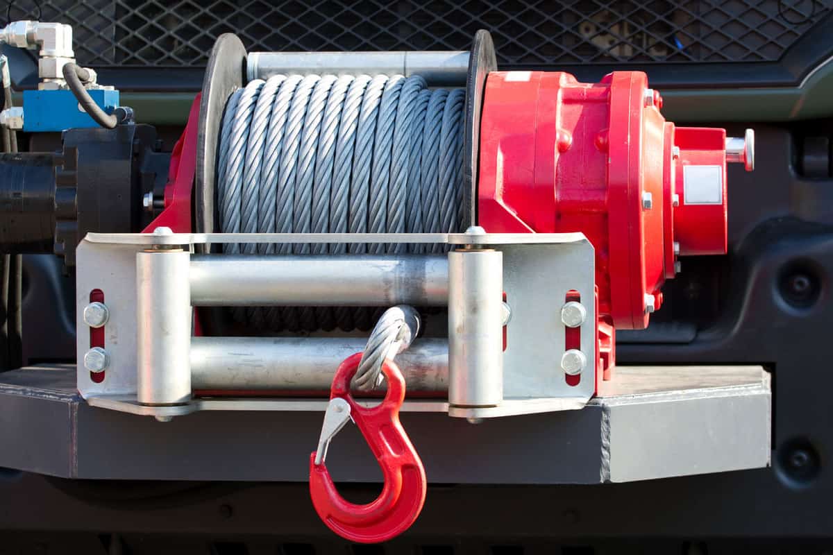 A red painted winch with huge cables welded to the chassis of the truck, Can You Mount A Winch On A Brush Guard? [And How To]