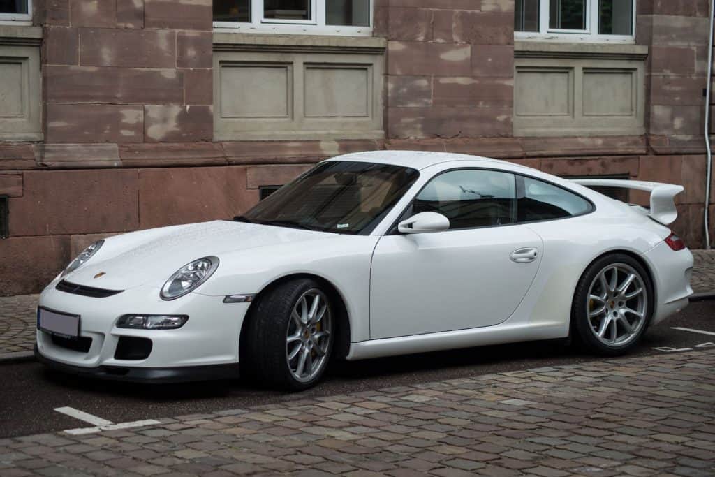 Luxurious white Porsche 91 parked on the side of the building