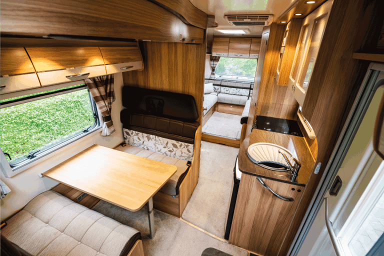 Luxury large open plan motor home interior with seating area and table for several occupants. Large window letting in a lot of daylight. interior with no people. RV USB Outlets Not Working - What To Do
