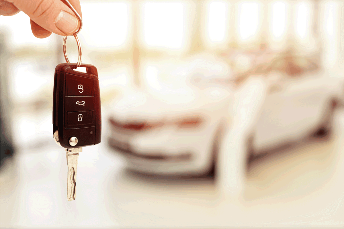 car sales showroom and person holding car key in hands