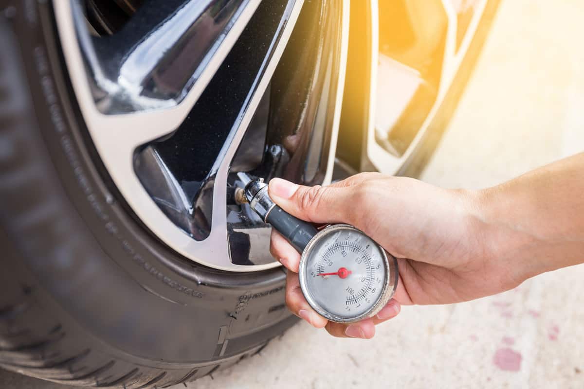 A car owner checking the tire pressure of his car