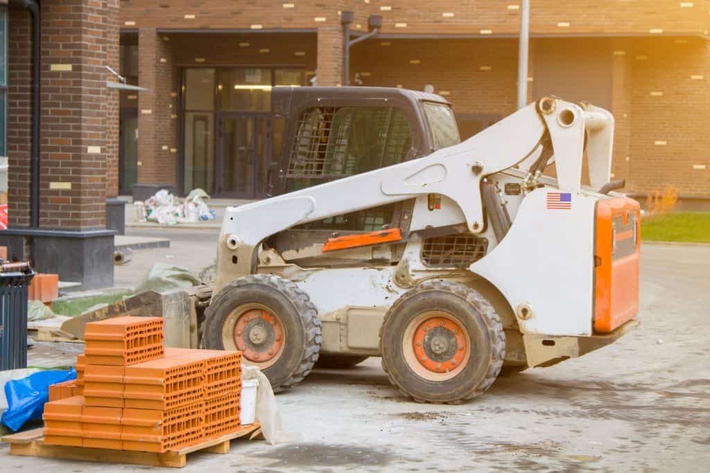 A filtered photo of a skid loader in front of a building