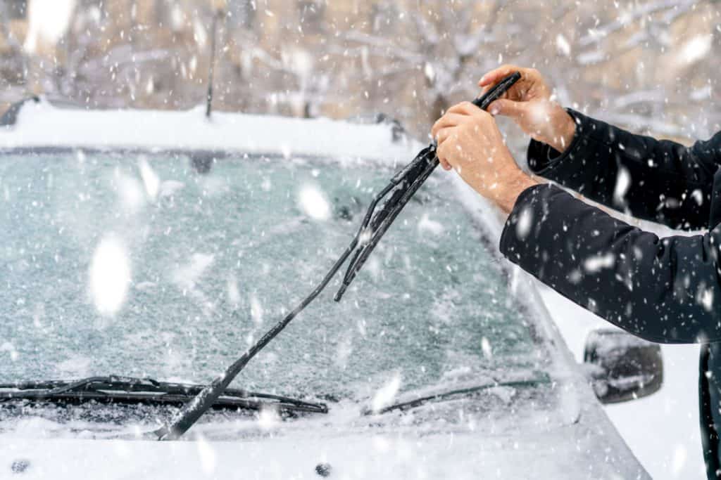 A man adjusting the wipers of the car