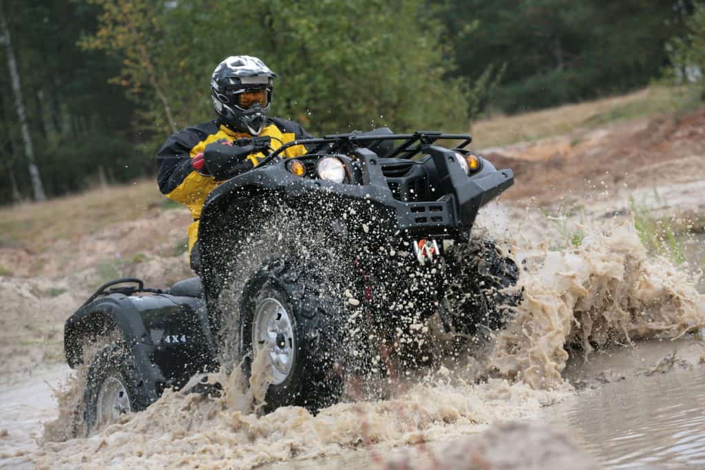 A man driving a big and powerful ATV on the mud