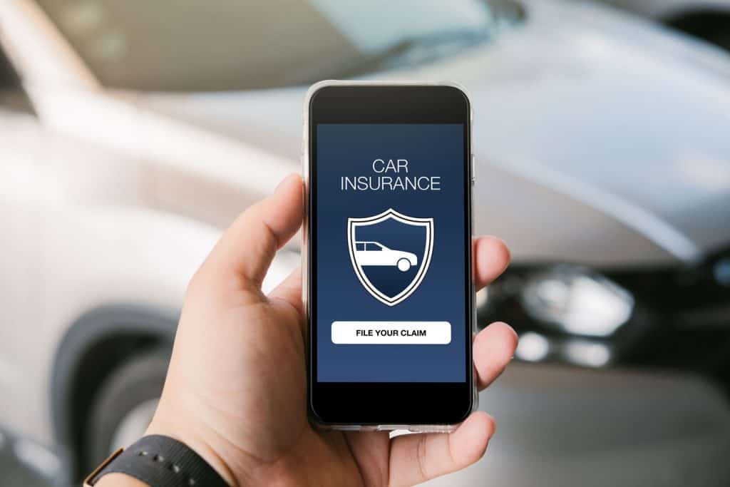 A man holding his phone showing a car insurance app