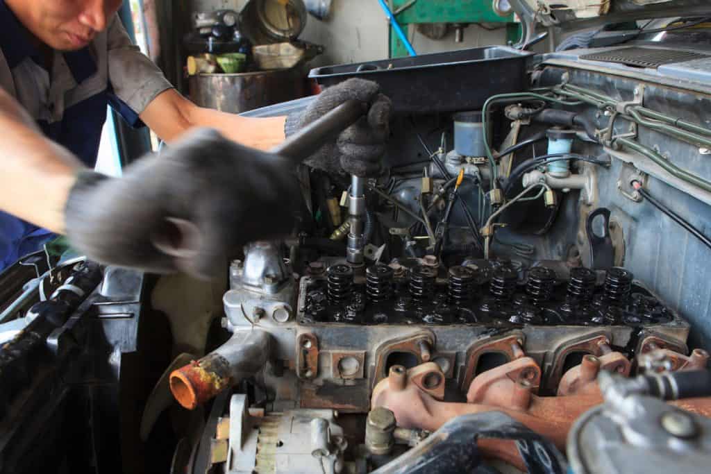 A mechanic doing a manual repair in the cylinder of a diesel engine
