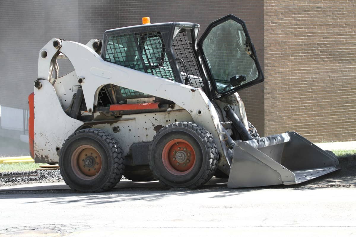 A white Skid loader with the operators door left open, What Year Is My Bobcat? [By Serial Number]