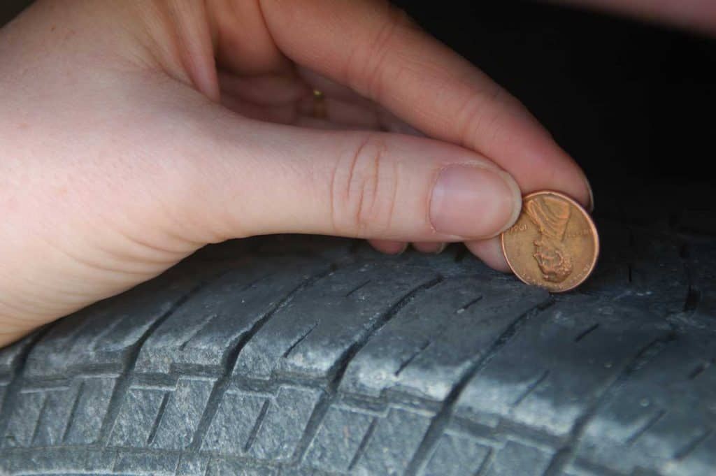 A woman does the penny test on her tire treads