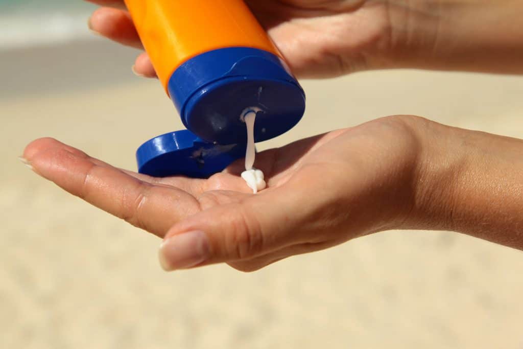 A woman putting on sunscreen on her hand