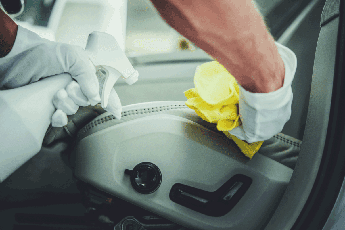 Automotive Car Detailing Worker Cleaning and Disinfecting Vehicle Interior Using Professional Detergents
