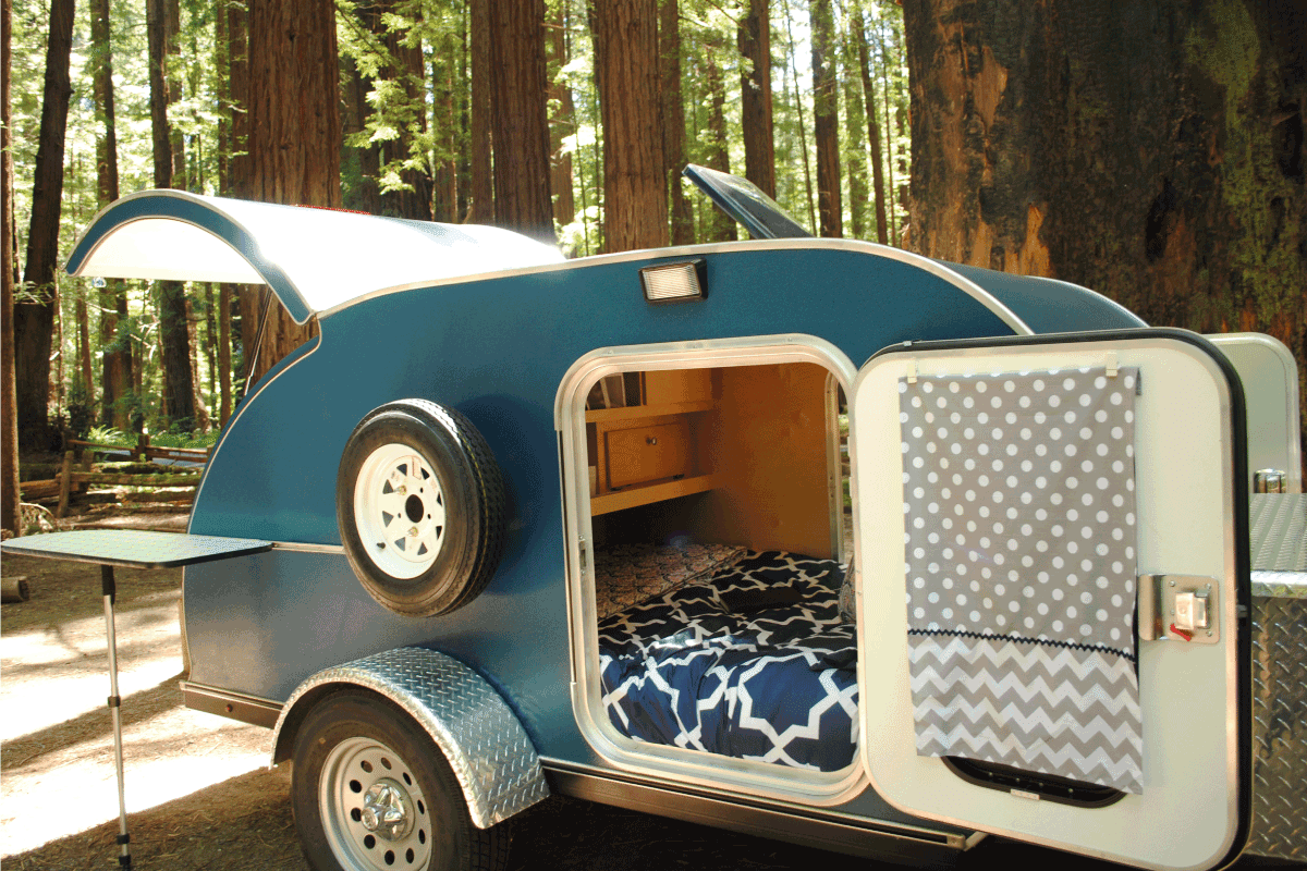Blue teardrop camping trailer with doors open and view to interior, setup at a campsite surrounded by redwood trees. What Size Travel Trailer Can A Tundra Pull