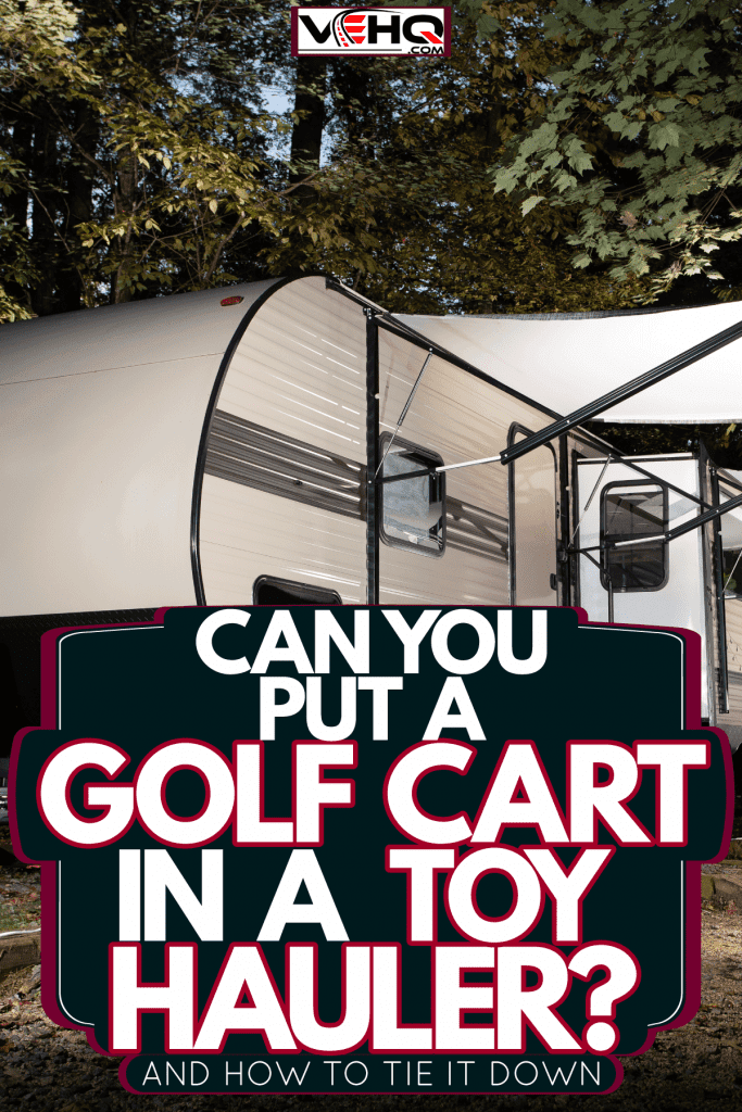 A huge white toy hauler with awning deployed and chairs set up outisde, Can You Put A Golf Cart In A Toy Hauler? [And How To Tie It Down]