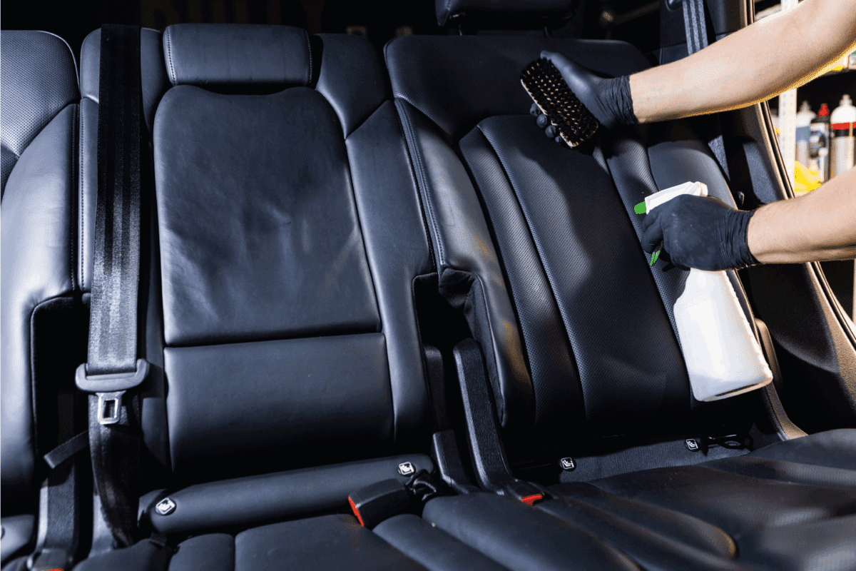 Car care concept, detailing and cleaning car interiors. Worker spraying cleaning solution on car upholstery