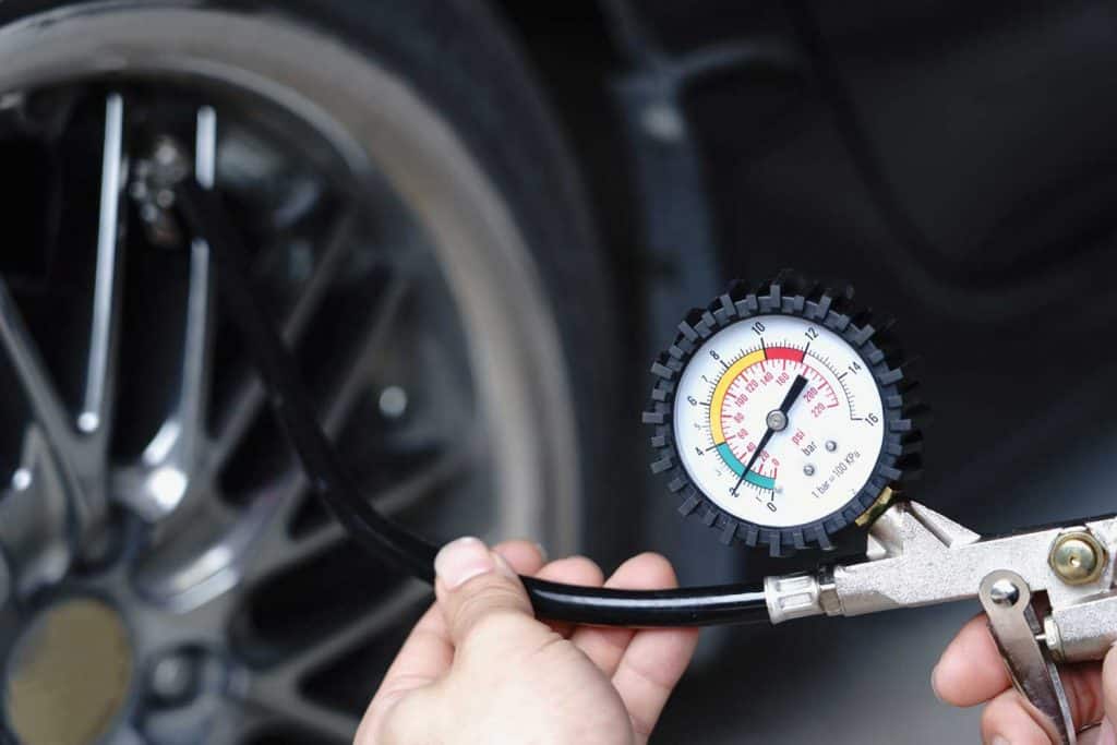Close up mechanic inflating tire hand holding gauge pressure for checking and filling air in car tire