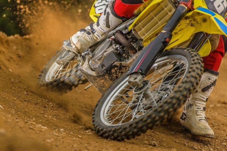 Close-up of motocross rider riding bike on dirt track, low section., How Long Do Motorcycle Tires Last?