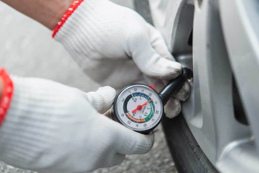 Hand holding pressure gauge for checking tire pressure