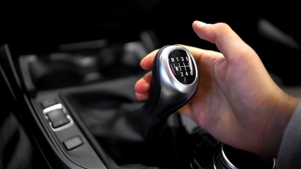 Male hand holding manual gearbox in car