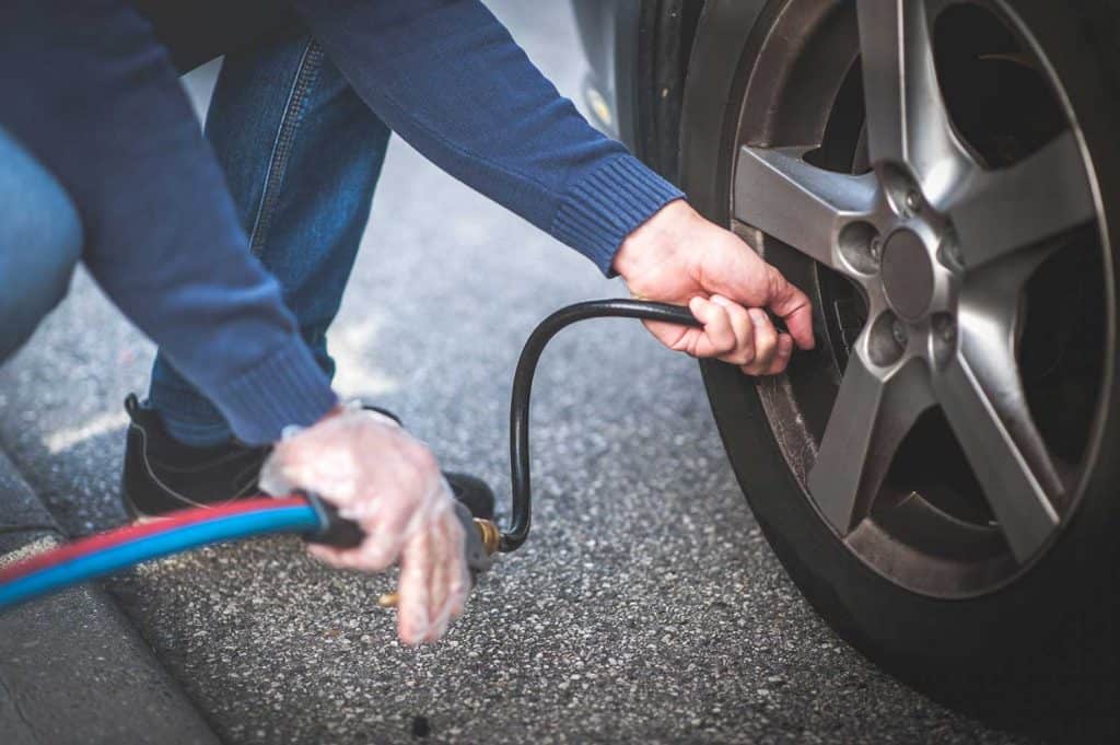 Man checking pressure and inflating car tire