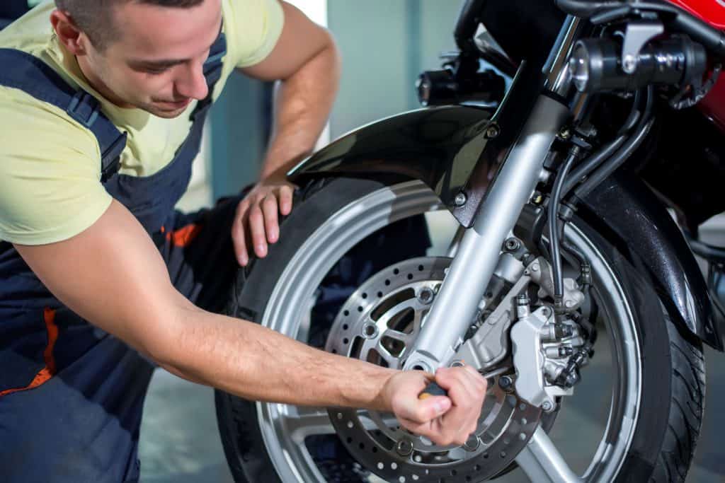 Man repairing motorcycle front tire