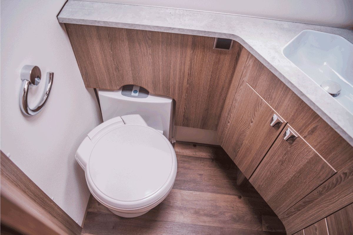 RV toilet with brown wood theme, clean toilet seat and empty tissue holder. How To Dissolve Toilet Paper In RV