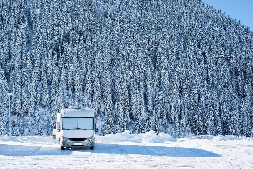 Recreational vehicle driving through a snow covered forest