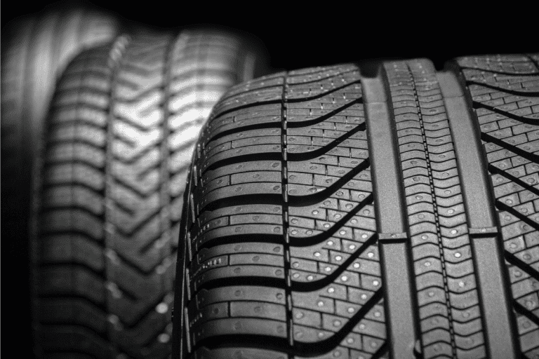 Row of car tires with a profile close-up on a black background. brand new and modern tires. How Often Should Tires Be Replaced?