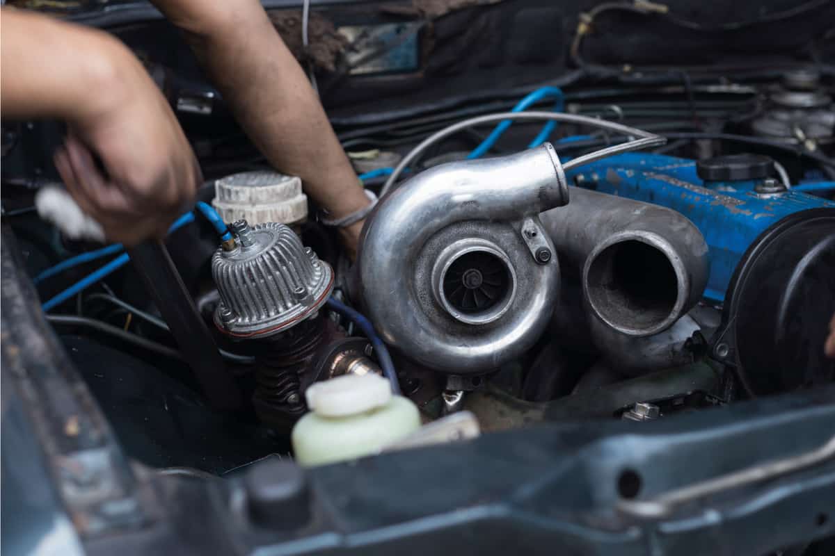 mechanic removing Turbo charger on car engine for repair
