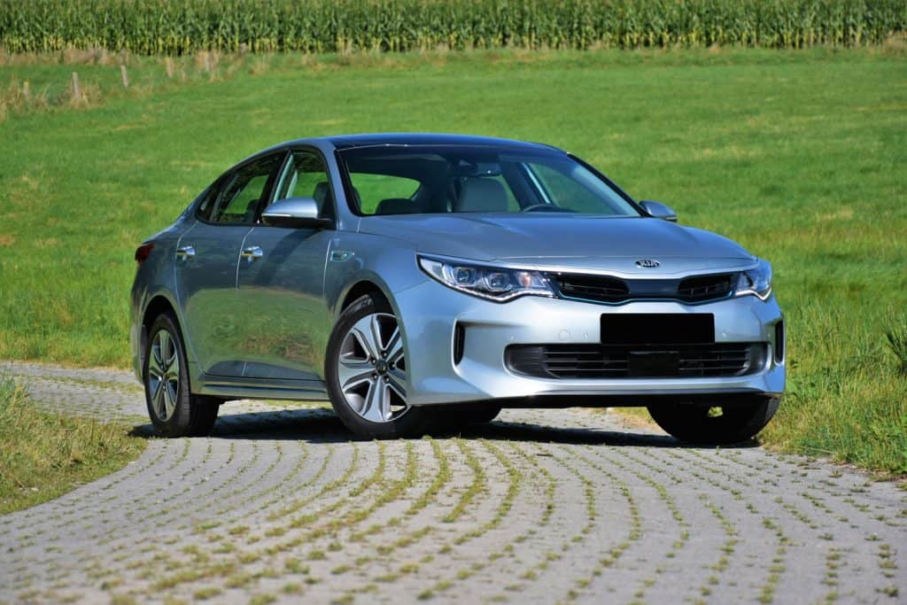 A detailed photo of a Kia Optima parked on a small road