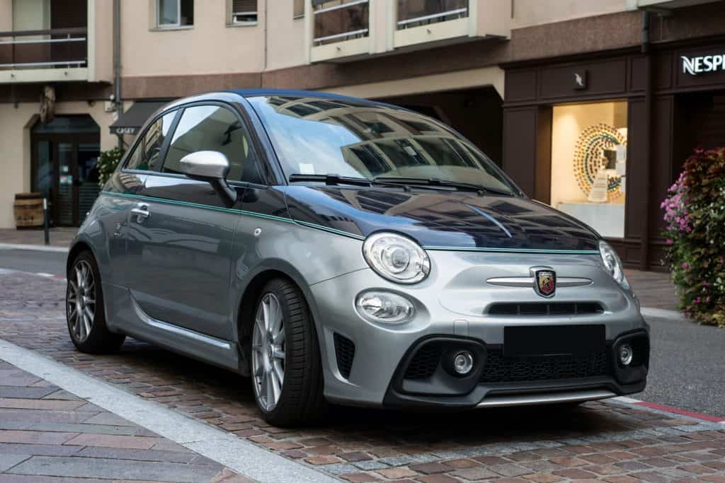 A front view of a fiat abarth parked on the streets of a beautiful city
