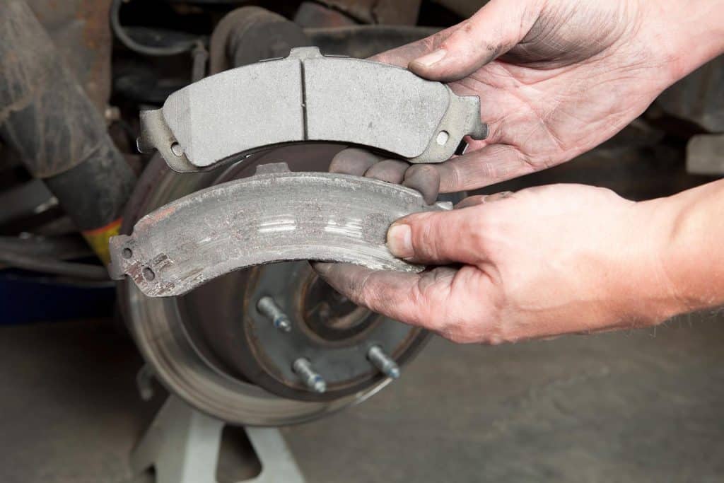 A mechanic hands are displaying a worn to the metal brake pads