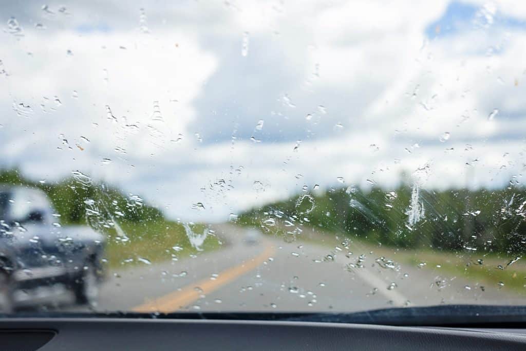 A messy windshield covered with bug guts and road dirt.