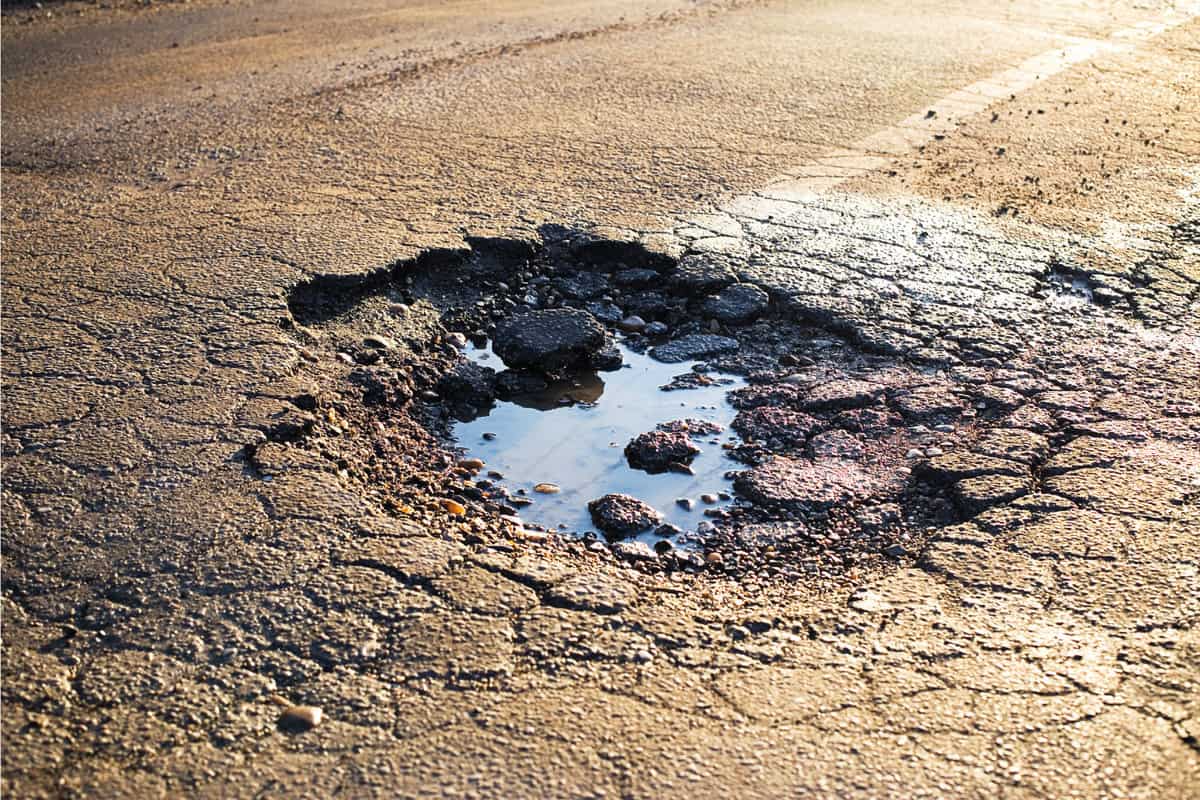 A road damaged by rain and snow, that is in need of maintenance. Broken asphalt pavement