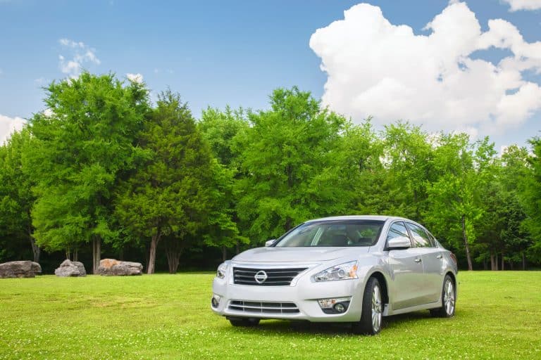 A silver redesigned 2013 model year Nissan Altima four door car, parked in the grass of an empty field, Nissan Altima Won't Start—What Could Be Wrong?