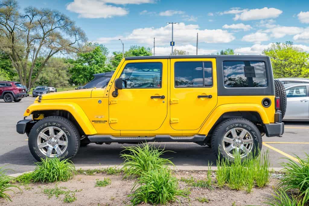 A yellow colored Jeep Wrangler Sahara Unlimited SUV is parked in a parking lot